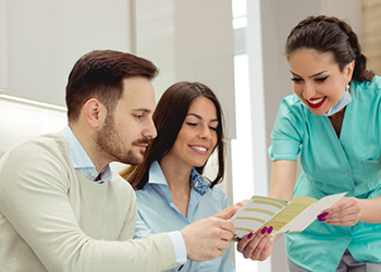 Dental team member showing a pamphlet to two patients