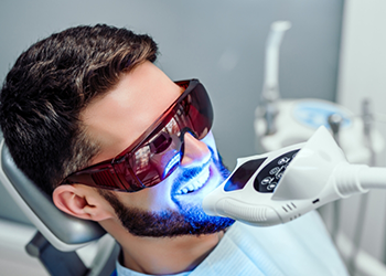 Man in dental chair receiving professional teeth whitening