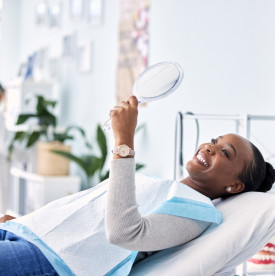 Woman in the dental chair grinning as she looks in a mirror