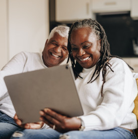Couple sitting on their couch and looking at a tablet together