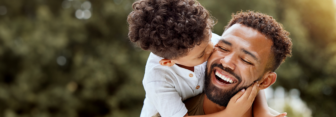 Young child kissing their father on the cheek