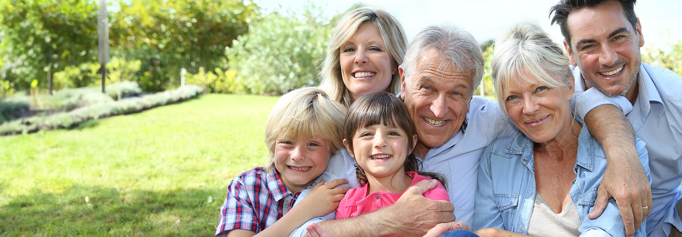 Senior couple with dentures in Londonderry smiling outdoors with their family