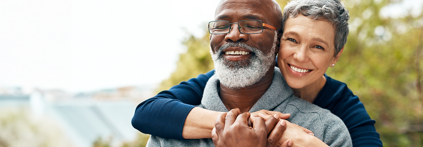 Older man and woman hugging and smiling after gum disease treatment in Londonderry