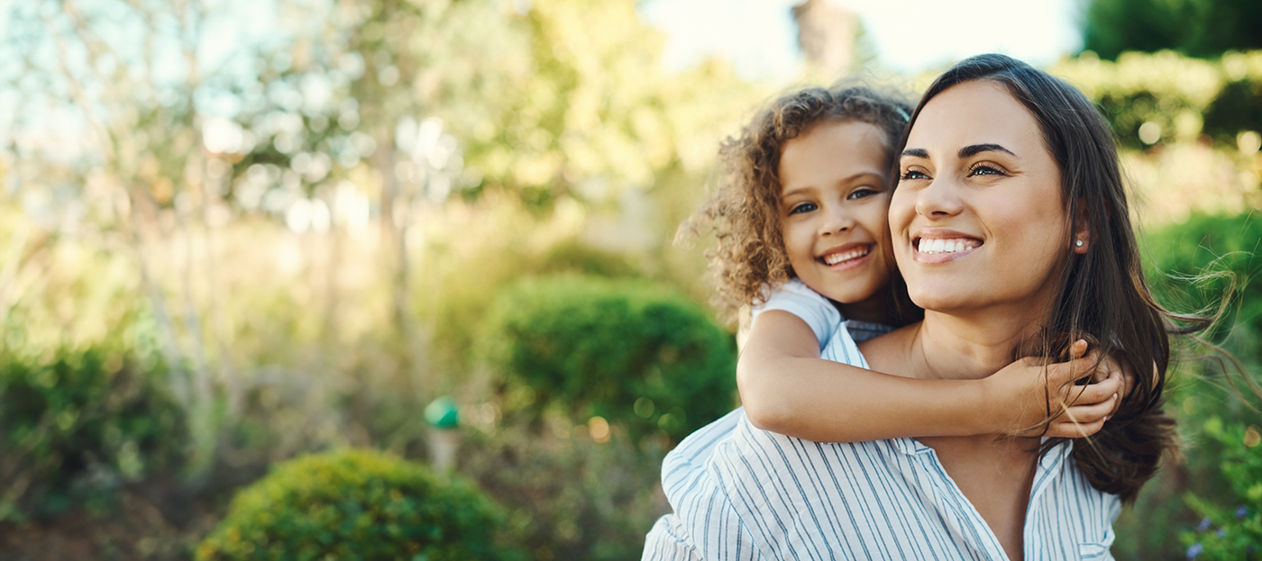 Smiling woman giving her young daughter a piggyback ride