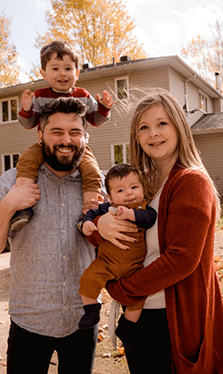 Smiling family of four standing in their front yard