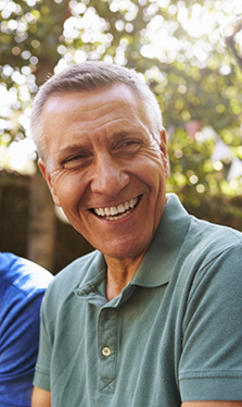 Older man laughing with friends outdoors