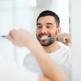 Man smiling while brushing his teeth