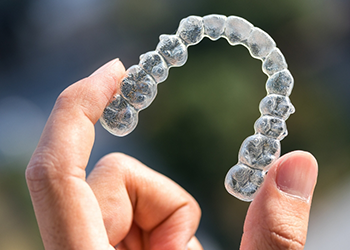 Hand holding an Invisalign clear aligner