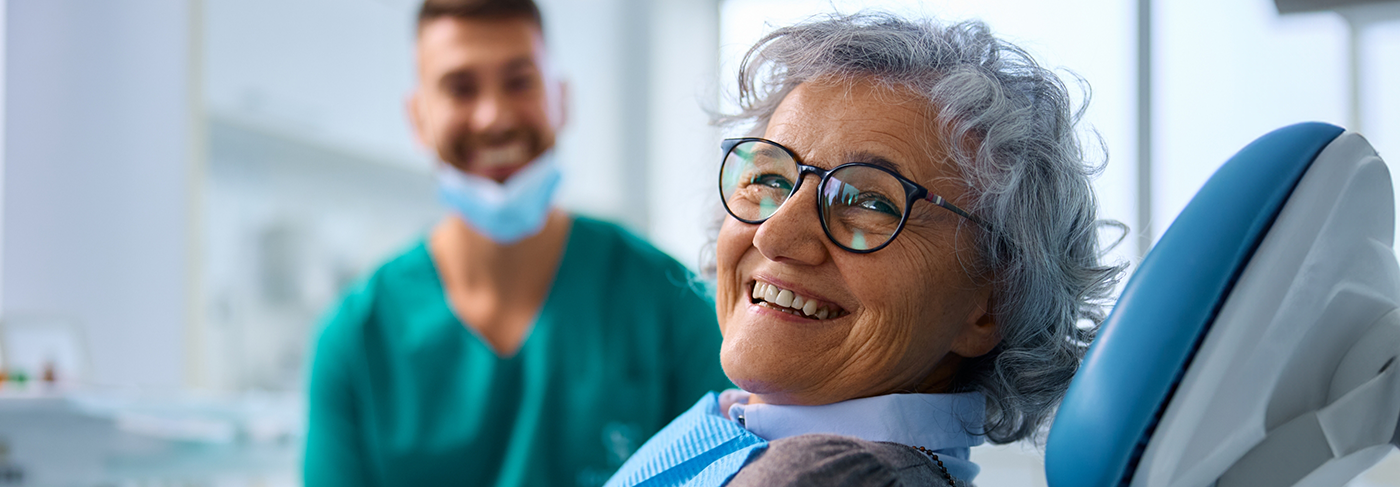 Older woman sitting in dental chair and grinning