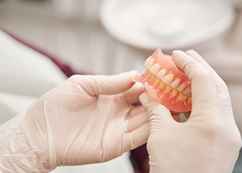 Gloved hands holding a set of full dentures