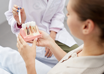 Dentist showing a patient a model of a dental implant