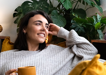 Young woman in gray sweater sitting on couch