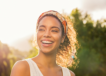 Woman with ponytail grinning outdoors on sunny day