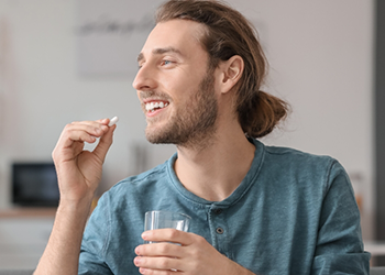 Man taking a pill with a glass of water