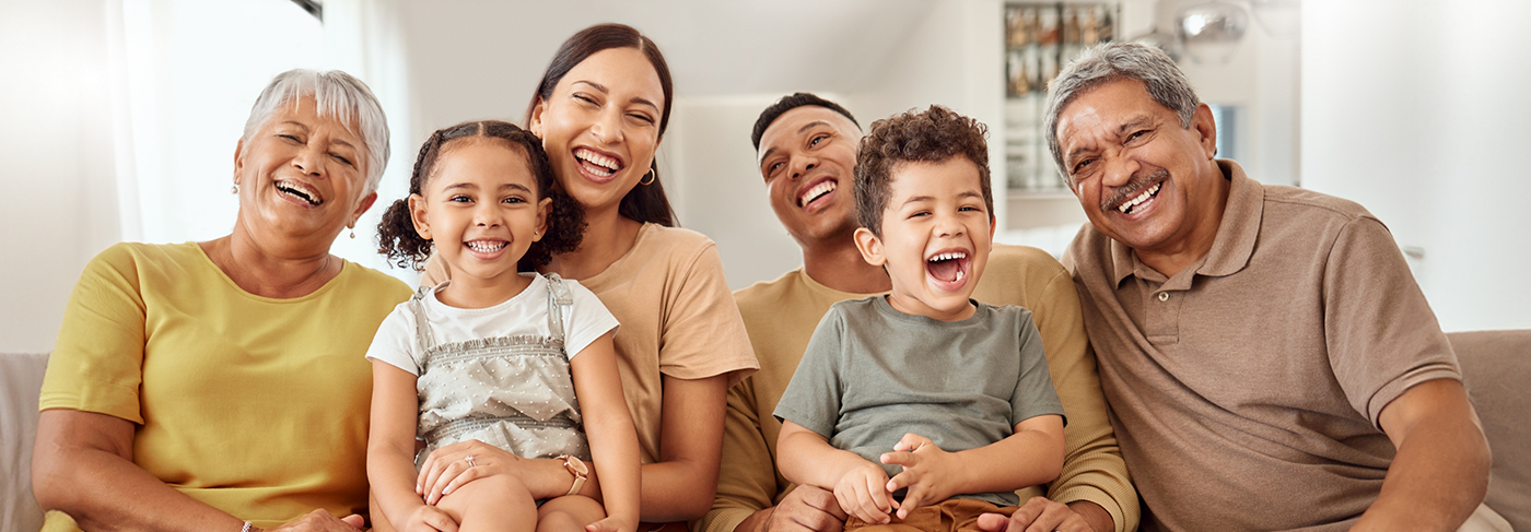 Three generations of smiling family sitting on couch after preventive dentistry checkups