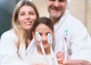 Parents and child holding their toothbrushes together