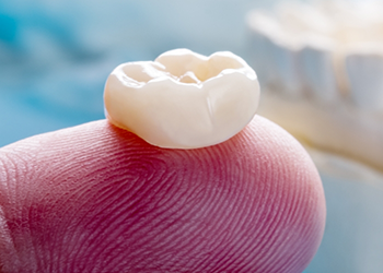 Close up of a dental crown resting on a finger