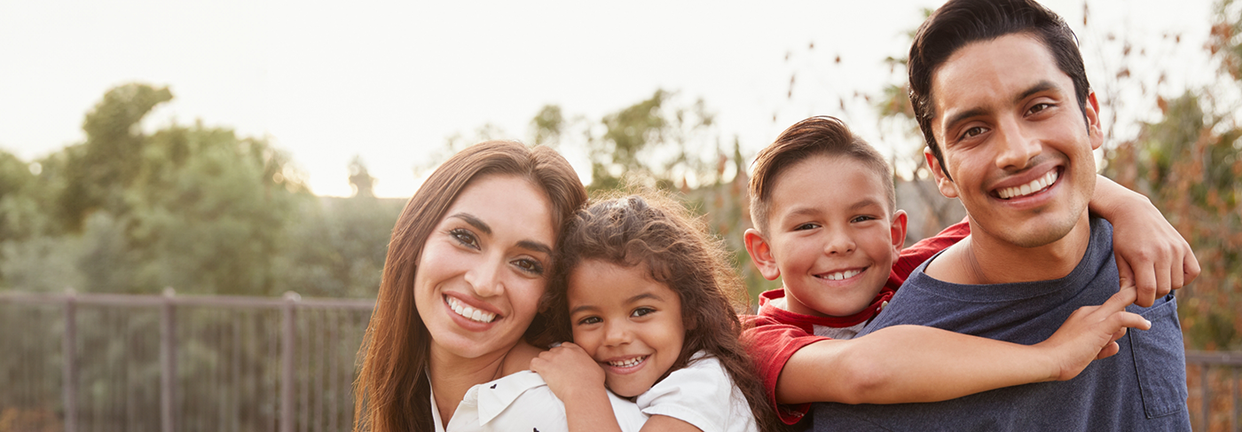 Family of four grinning outdoors after root canal treatment in Londonderry