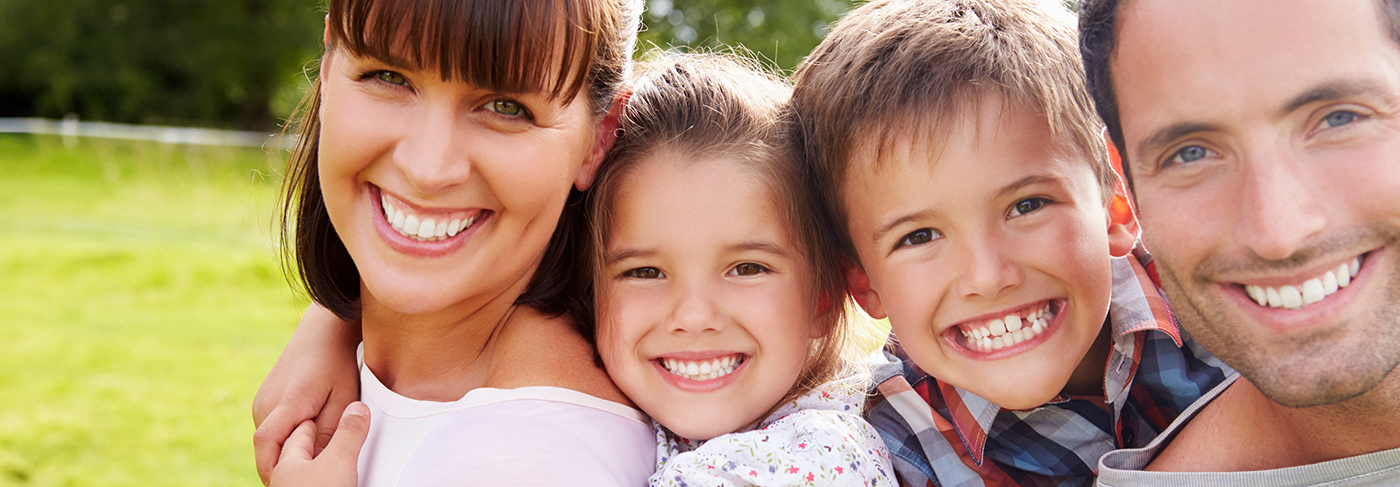 Family of four grinning outdoors after teeth whitening in Londonderry