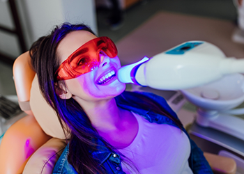 Woman in dental chair receiving professional teeth whitening